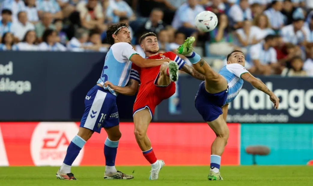 FOTOGRAFÍA. MÁLAGA, 09 DE OCTUBRE DE 2026. El delantero del Espanyol Roberto Fernández Maeso (c) pelea un balón con Recio (i) y Rafa, ambos del Málaga, durante el partido de LaLiga de fútbol que Málaga CF y RCD Espanyol disputan este viernes en el estadio de La Rosaleda. EFE
