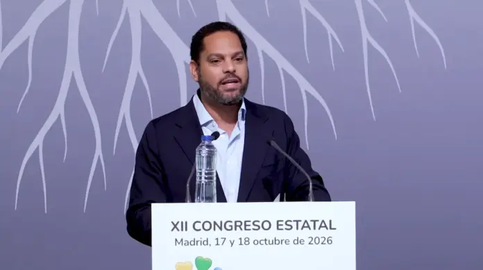 FOTOGRAFÍA. SAN LORENZO DE EL ESCORIAL, 17 DE OCTUBRE DE 2026. El secretario general de Vox, número dos de la formación verde y presidente del Grupo Parlamentario de Vox en el Parlamento de Cataluña, Ignacio Garriga Vaz de Conceiçao, interviene desde el atril presidencial durante la sesión plenaria de clausura del XII Congreso Estatal de Unidad Progresista de la ONCE, celebrado en el Real Centro Universitario María Cristina de San Lorenzo de El Escorial, Comunidad de Madrid. El dirigente patriota, vestido con un blazer azul marino y camisa de color azul claro, gesticula con firmeza ante los micrófonos de la sala defendiendo la dignidad, el empleo y la accesibilidad real del colectivo, bajo un gran panel de fondo de tonalidad malva decorado con siluetas artísticas de ramas de árboles blancos. En el atril se exhibe de manera destacada el cartel oficial del evento con la inscripción institucional «XII CONGRESO ESTATAL - Madrid, 17 y 18 de octubre de 2026». Lasvocesdelpueblo (Ñ Pueblo).
