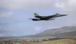 FOTOGRAFÍA. (BASE AÉREA DE GANDO, LAS PALMAS DE GRAN CANARIA, 15 DE NOVIEMBRE DE 2021). Un avión de combate McDonnell Douglas F/A-18 Hornet (identificado con el numeral de cola 12-07 y el código de fuselaje C.15-48 en su deriva trasera) del Ejército del Aire y del Espacio de España realiza una maniobra de despegue a gran velocidad elevando el morro hacia el cuadrante superior derecho. La potente aeronave militar, que lleva acoplados depósitos de combustible externos subalares para misiones de largo alcance, vuela a baja cota dejando una estela sutil sobre un fondo geográfico escarpado de montañas áridas típicas del archipiélago canario. En la loma inferior izquierda se aprecia un núcleo de viviendas y construcciones de color blanco agrupadas en terrazas de ladera, bajo un cielo semicubierto por nubes bajas y densas que envuelven la escena operativa de la base. EFE