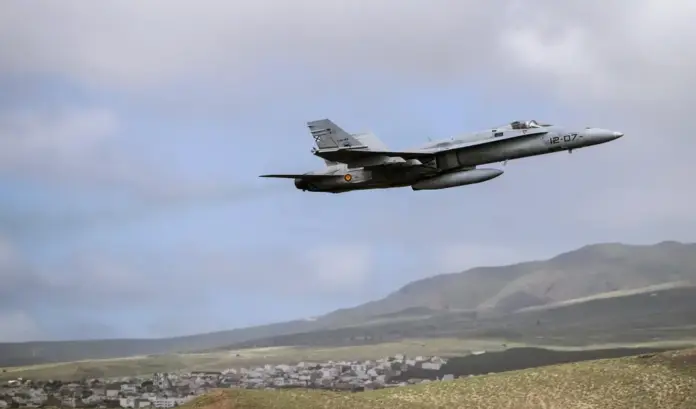 La OTAN activa los cazas españoles en la frontera rumana ante la amenaza inminente de objetos hostiles FOTOGRAFÍA. (BASE AÉREA DE GANDO, LAS PALMAS DE GRAN CANARIA, 15 DE NOVIEMBRE DE 2021). Un avión de combate McDonnell Douglas F/A-18 Hornet (identificado con el numeral de cola 12-07 y el código de fuselaje C.15-48 en su deriva trasera) del Ejército del Aire y del Espacio de España realiza una maniobra de despegue a gran velocidad elevando el morro hacia el cuadrante superior derecho. La potente aeronave militar, que lleva acoplados depósitos de combustible externos subalares para misiones de largo alcance, vuela a baja cota dejando una estela sutil sobre un fondo geográfico escarpado de montañas áridas típicas del archipiélago canario. En la loma inferior izquierda se aprecia un núcleo de viviendas y construcciones de color blanco agrupadas en terrazas de ladera, bajo un cielo semicubierto por nubes bajas y densas que envuelven la escena operativa de la base. EFE