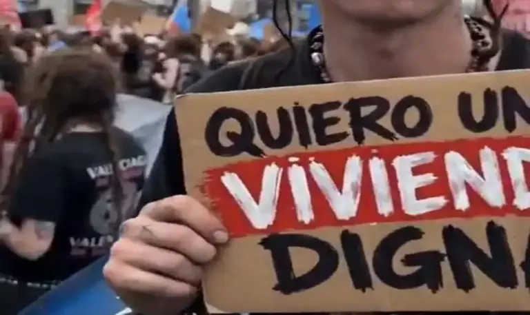 FOTOGRAFÍA. VALENCIA, 19 DE OCTUBRE DE 2026. Detalle de un activista de ultraizquierda reclamando una vivienda digna en un cartel improvisado, obviando completamente la realidad en el terreno: el esfuerzo, trabajo, el ahorro, etc., bajada d eimpuestos y trabas de la administración zurda de La Moncloa para, ahora sí, comprarse una vivienda. Captura vídeo/Lasvocesdelpueblo (Ñ Pueblo)