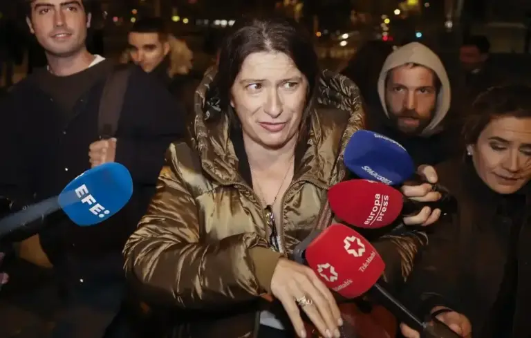FOTOGRAFÍA. MADRID, 26 DE NOVIEMBRE DE 2025. La exmilitante del PSOE y cabecilla de la red de fontanería de Moncloa, María Leire Díez Castro, avanza con rostro desencajado, mirada de evidente incomodidad y gesto tenso a su salida de los juzgados de la Plaza de Castilla de Madrid tras prestar declaración obligada en calidad de investigada ante el juez de instrucción. En la imagen, captada en un primer plano de seguimiento periodístico nocturno por los servicios gráficos de la Agencia EFE, se aprecia a la encausada vistiendo un abrigo acolchado de plumas de color bronce metalizado con capucha, rodeada por una nube de informadores y cámaras. En la escena, varios periodistas sostienen micrófonos corporativos de televisión apuntando directamente hacia Díez para recabar sus explicaciones, destacando de izquierda a derecha el micrófono azul con el logotipo de la Agencia EFE, el micrófono rojo de la cadena autonómica Tele Madrid y el distintivo corporativo de Europa Press. En el fondo difuminado, caminan a su lado varios acompañantes y miembros de su equipo de defensa jurídica con capuchas y semblantes serios entre la oscuridad del exterior de los juzgados madrileños. EFE